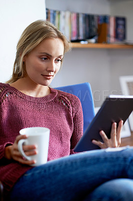 Buy stock photo Shot of a young woman using a digital tablet while relaxing at home