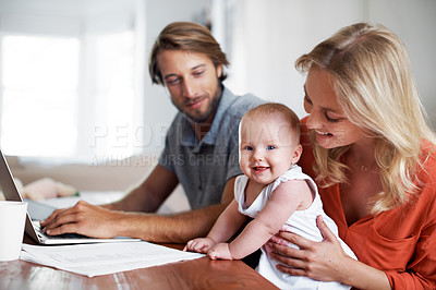 Buy stock photo Shot of a couple using a laptop while cradling their baby