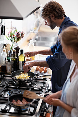 Buy stock photo Shot of a young couple cooking breakfast together in the kitchen