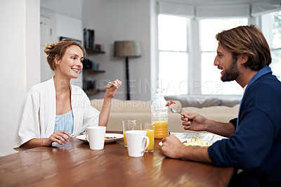 Buy stock photo Shot of a young couple eating breakfast together at home