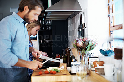 Buy stock photo Shot of a young couple cooking together in the kitchen