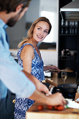 Buy stock photo Shot of a young couple cooking together in the kitchen