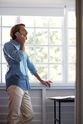 Buy stock photo Shot of a young man talking on his cellphone at home