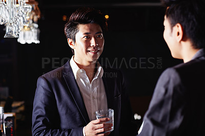 Buy stock photo Shot of two male friends drinking and talking together in a club