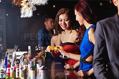 Buy stock photo Shot of two attractive young women doing shots in a night club