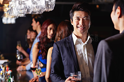 Buy stock photo Shot of two male friends drinking and talking together in a club