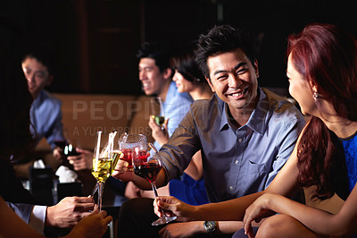 Buy stock photo Shot of a group of friends sitting in a nightclub enjoying drinks 