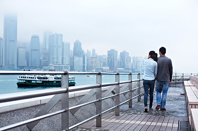 Buy stock photo Rearview shot of a young couple walking along the Hong Kong waterfront