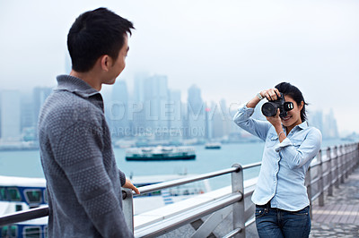 Buy stock photo Shot of a young couple taking photos of each other in front of the Hong Kong skyline