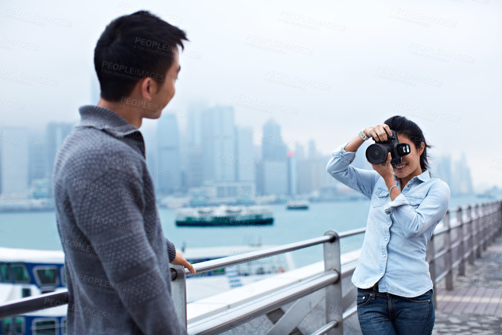 Buy stock photo Shot of a young couple taking photos of each other in front of the Hong Kong skyline
