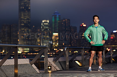 Buy stock photo Portrait of an athletic young man standing in front of the Hong Kong skyline at night