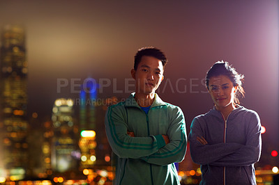 Buy stock photo Portrait of two fit young people standing in front of the Hong Kong skyline at night