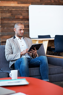 Buy stock photo Shot of a handsome man using his laptop in a modern office