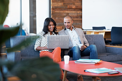 Buy stock photo Shot of two colleagues using a laptop at the office
