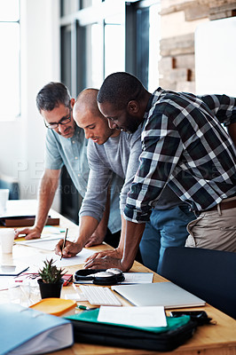 Buy stock photo Shot of a group of colleagues going through some paperwork