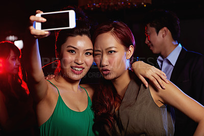 Buy stock photo Shot of a two attractive female friends taking a selfie in a nightclub