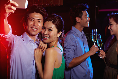 Buy stock photo Shot of an attractive young asian couple taking a selfie in a nightclub