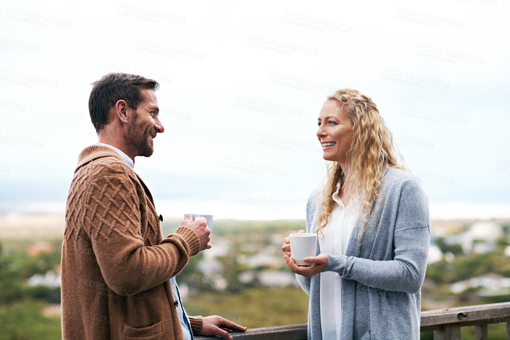 Buy stock photo Talking, happy and couple on balcony with coffee for bonding, conversation and connection. Marriage, morning and man with woman outdoor with drink, chat and laugh for love, relationship and view