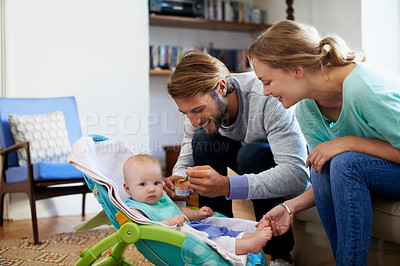 Buy stock photo Shot of a young couple feeding their baby at home