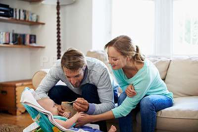 Buy stock photo Shot of a young couple feeding their baby at home