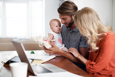 Buy stock photo Shot of a couple using a laptop while cradling their baby