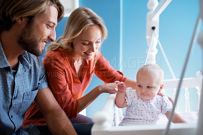 Buy stock photo Shot of a couple playing with their baby lying in a crib