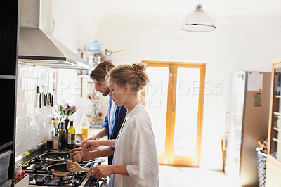 Buy stock photo Shot of a young couple cooking breakfast together in the kitchen