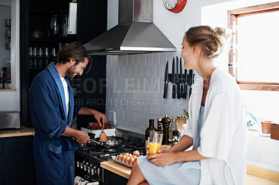 Buy stock photo Shot of a young couple cooking breakfast together in the kitchen