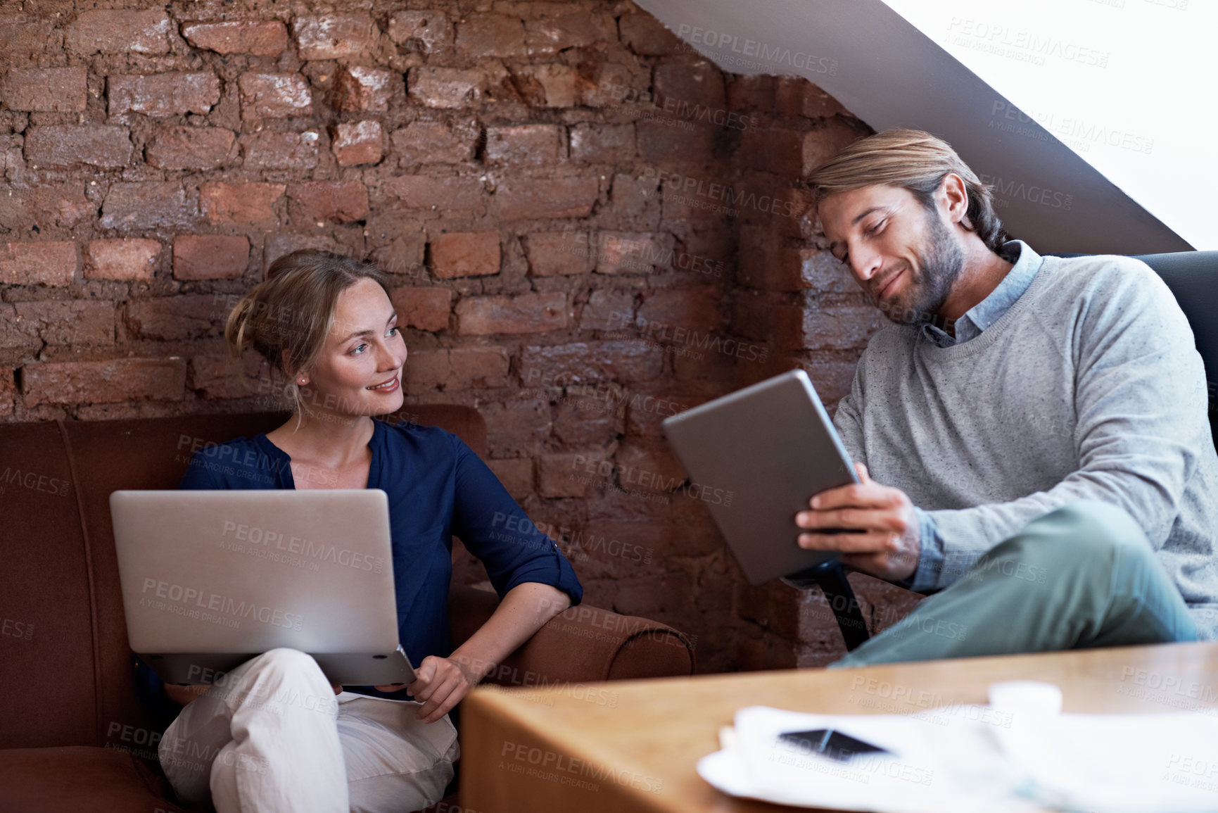 Buy stock photo Shot of a young couple using a digital tablet and laptop while relaxing at home