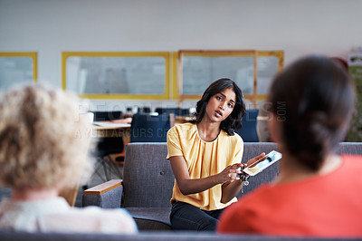 Buy stock photo Cropped shot of an attractive young businesswomen showing her two colleagues something on a tablet