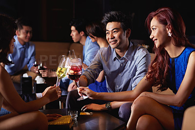Buy stock photo Shot of a group of friends sitting in a nightclub enjoying drinks 