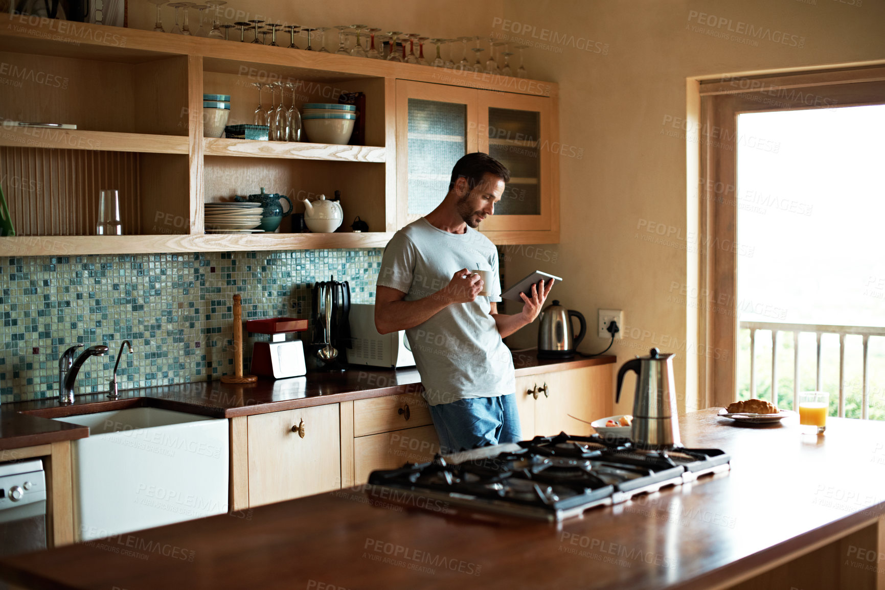 Buy stock photo Cropped shot of a handsome man eating breakfast while using a tablet