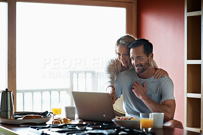 Buy stock photo Cropped shot of a couple using a laptop in the middle of breakfast