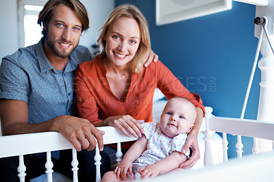 Buy stock photo Portrait of a young couple with their baby daughter who's lying in a crib