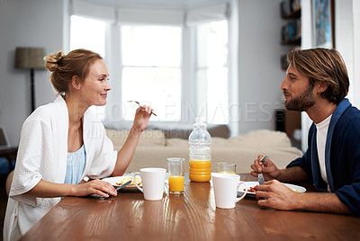 Buy stock photo Shot of a loving young couple eating breakfast at their dining table