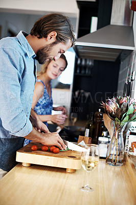 Buy stock photo Shot of a young couple cooking together in the kitchen