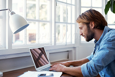 Buy stock photo Shot of a young man working on his laptop at home