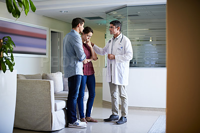 Buy stock photo Shot of a doctor delivering news to a couple in a hospital waiting room