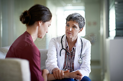 Buy stock photo Shot of a compassionate doctor comforting a young woman in a hospital waiting room