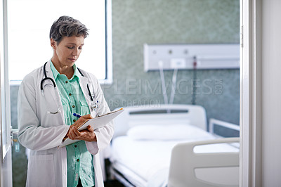 Buy stock photo Shot of a doctor taking down notes in a hospital