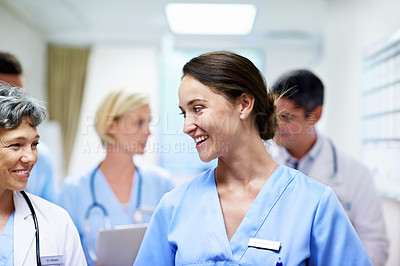 Buy stock photo Shot of a team of doctors walking and talking in a hospital corridor