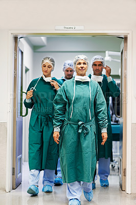 Buy stock photo Shot of a team of surgeons walking out of an operating room
