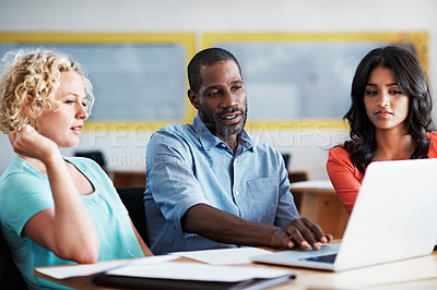 Buy stock photo Cropped shot of three businesspeople working on a laptop