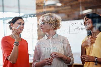 Buy stock photo Cropped shot of three businesswoman working on a glass wall