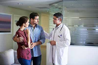 Buy stock photo Shot of a doctor delivering news to a couple in a hospital waiting room