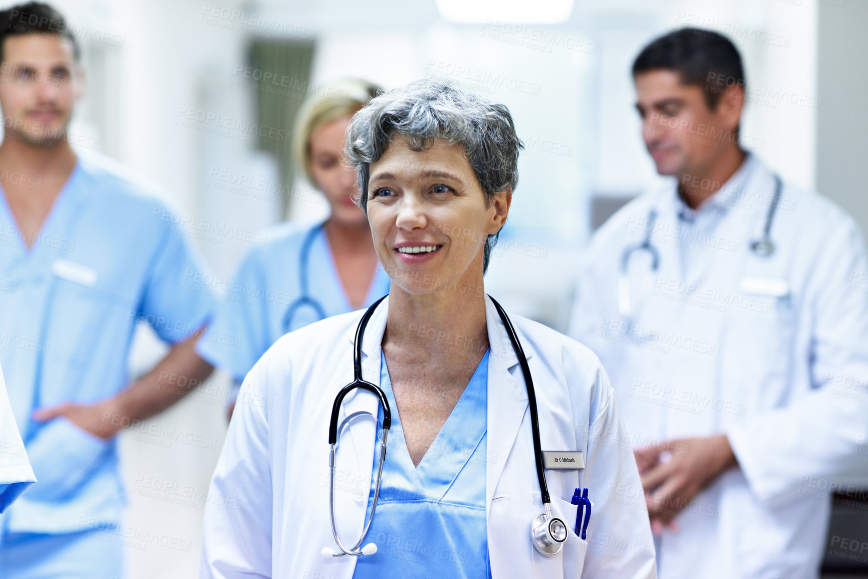 Buy stock photo Shot of a group of doctors walking down a hospital corridor