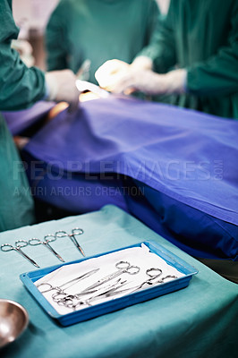 Buy stock photo Closeup shot of operating instruments on a table with doctors working in the background