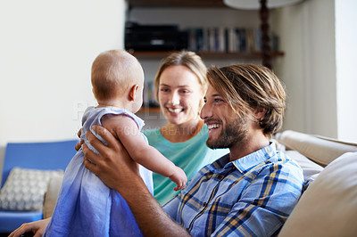 Buy stock photo Shot of a young couple playing with their baby at home