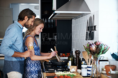 Buy stock photo Shot of a young couple cooking together in the kitchen