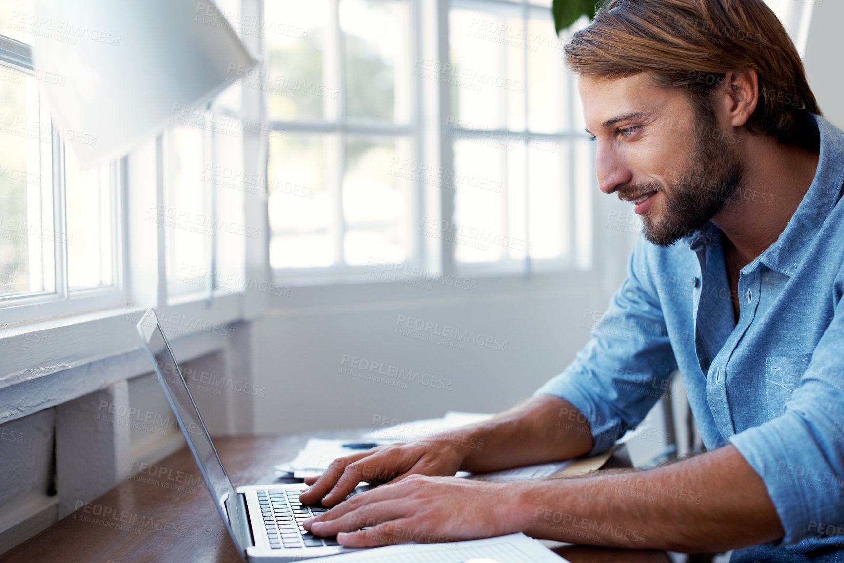 Buy stock photo Shot of a young man working on a laptop in his study at home